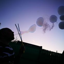 Low angle view of boy at bubbles against sky