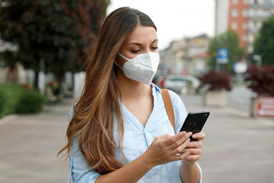 Young woman using mobile phone in city