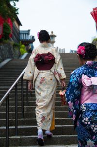 Rear view of women in kimono walking on steps