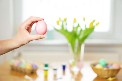 Female hand holding a pink painted easter egg. homemade food decoration. preparation for easter.