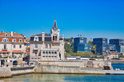 Buildings at waterfront against blue sky