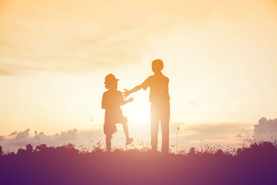 Silhouette people standing on land against sky during sunset