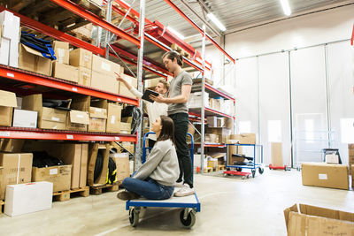 Male and female coworkers examining while standing at warehouse