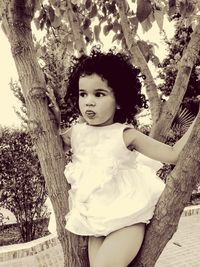 Portrait of cute girl standing by tree