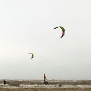 People kiteboarding on sea against clear sky