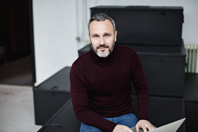 Portrait of confident businessman using laptop while sitting at office