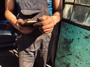 Midsection of mechanic using mobile phone at garage