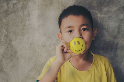 Portrait of boy holding ball against wall