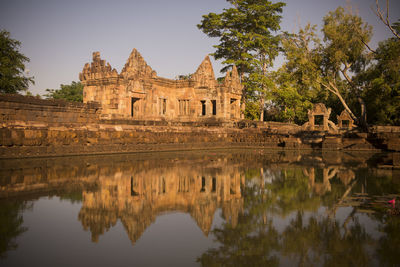 Prasat ta muen thom temple by lake against clear sky