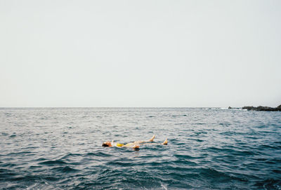 Man swimming in sea against clear sky