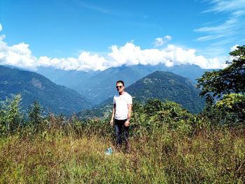 Young man standing on mountain against sky