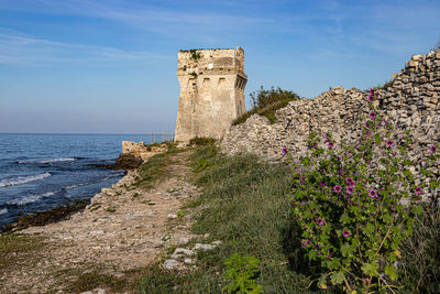 Scenic view of sea and ancient tower against sky