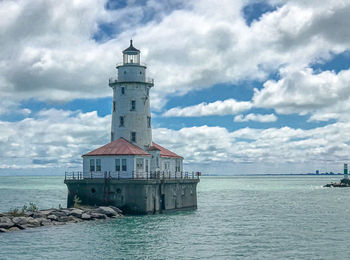 Lighthouse by sea against sky