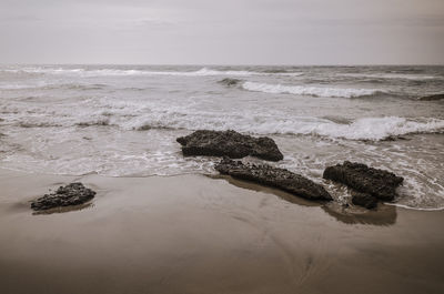 Scenic view of rocks on beach against sky