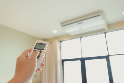 Midsection of person holding smart phone against wall