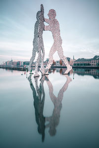 Reflection of built structure in water against sky