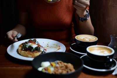 Midsection of woman holding food served on table