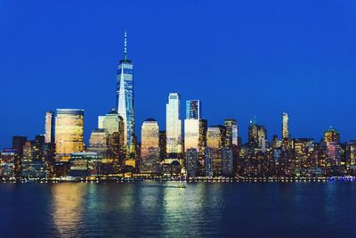 Illuminated buildings in city against blue sky