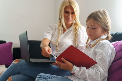 Woman using mobile phone while sitting in laptop