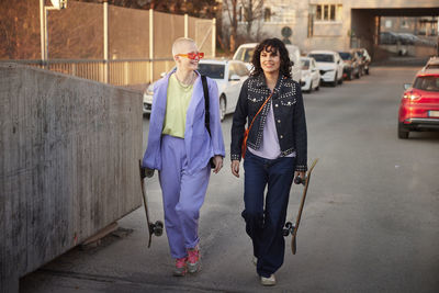 Young women walking together while carrying skateboards