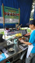 Side view of a man preparing food for sale at market