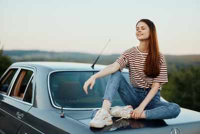 Portrait of young woman holding car