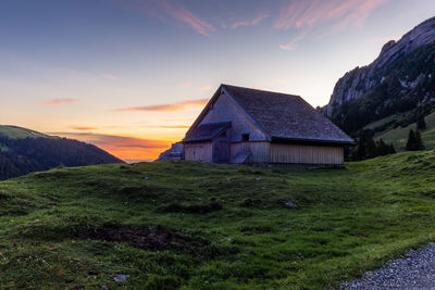 House on mountain against sky during sunset