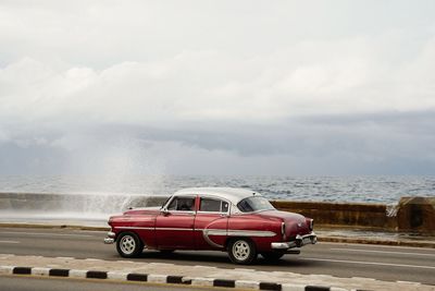 Vintage car on beach against sky
