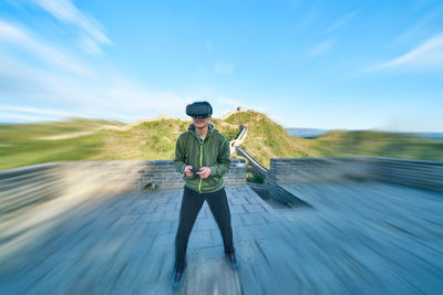 Man enjoying virtual reality simulator while standing on great wall of china