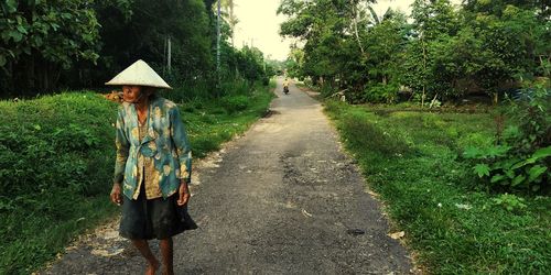 Woman walking on road amidst trees