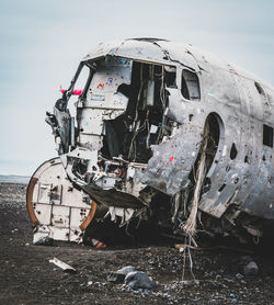 Damaged airplane on land against sky