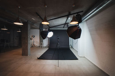 Interior of modern photo studio with octaboxes and professional photo camera on tripod against black background