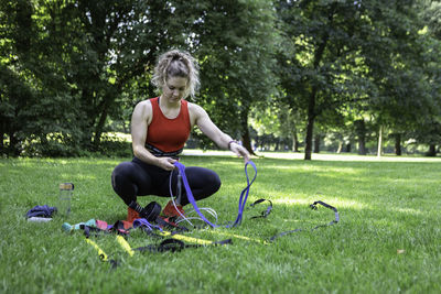 Full length of woman sitting on grass against trees