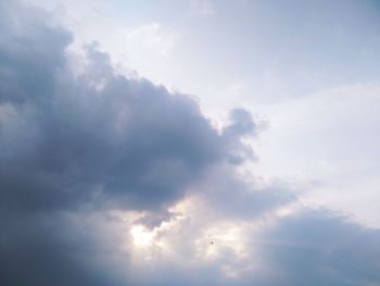 Low angle view of sunlight streaming through clouds