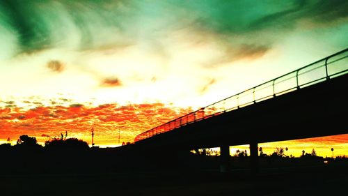 Low angle view of silhouette bridge against dramatic sky