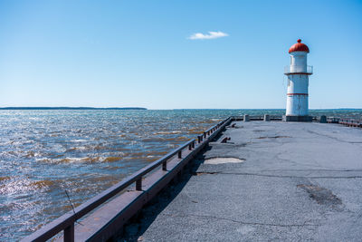 Lighthouse by sea against sky