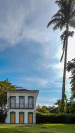 Built structure and trees by house against sky