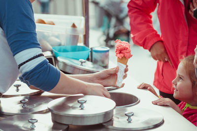 Rear view of vendor selling ice cream to girl on street