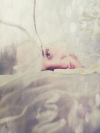 Close-up portrait of young woman lying on bed