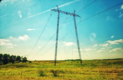 Low angle view of electricity pylon on field against sky