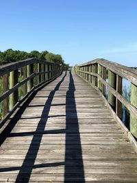View of wooden footbridge against clear blue sky