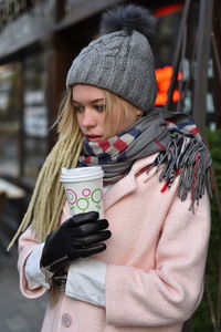 Young woman looking away while holding coffee cup in winter