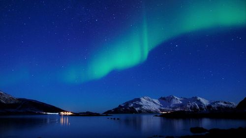 Scenic view of snowcapped mountains and northern lights against sky at night