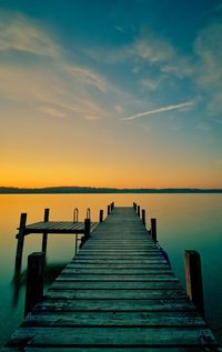 Wooden pier over sea against sky during sunset