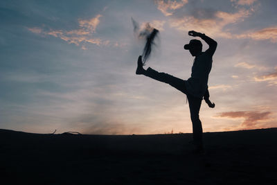 Silhouette man standing on land against sky during sunset