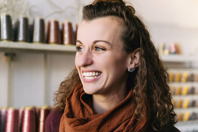 Joyful woman with curly hair smiling brightly in a craft shop