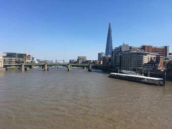 View of bridge over river by buildings against clear sky