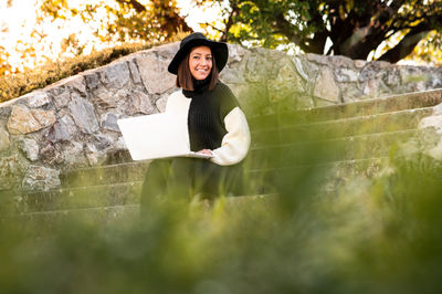 Portrait of young woman sitting on rock