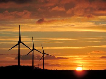 Silhouette of windmill against dramatic sky during sunset