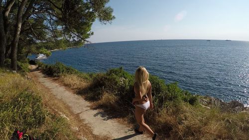 Woman standing by sea against sky